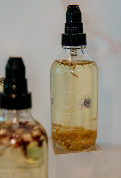 4oz clear glass bottle with black treatment pump top with botanical body oil with calendula flowers