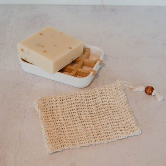Bar of soap in a soap dish with a natural sisal soap saver pouch. 